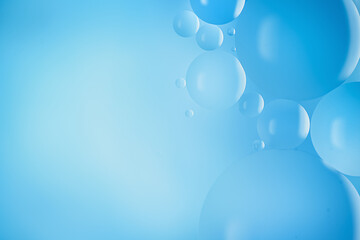 Sparkling droplets of serum and essence float on the surface of blue water. copy space