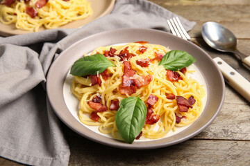 Plate with tasty pasta carbonara on wooden background