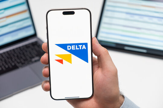 PRAGUE, CZECH REPUBLIC - JANUARY 21 2024: Delta logo on the screen of smartphone in mans hand on the workplace background. 