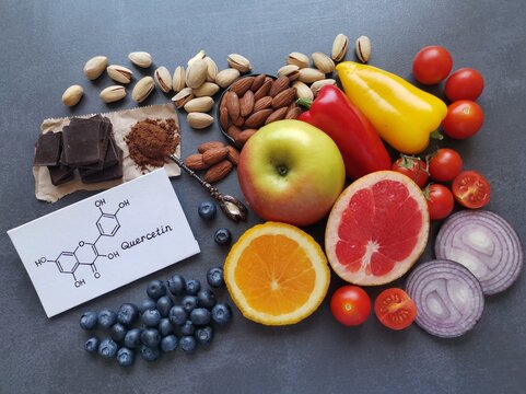 Structural chemical formula of quercetin with fresh fruit and vegetable. Quercetin is a plant pigment (flavonoid). It's found in many plants such as red onion, berries, tomato, nuts, citrus, apple.