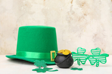 Pot with golden coins, plastic eyeglasses and leprechaun hat on light grunge background. St....