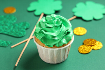 Tasty cupcake with decor for St. Patrick's Day on green background, closeup