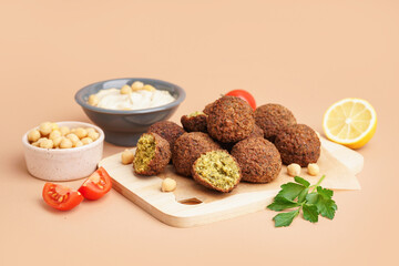 Board with delicious falafel balls, hummus and chickpea on beige background