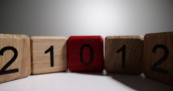 Wooden cubes with digits in descending order lead to red cube with zero. Lines of enumerated cubes stand on white surface in studio