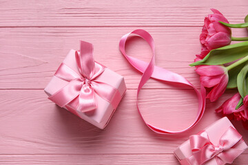 Composition with figure 8 made of ribbon, flowers and gift boxes on pink wooden background. International Women's Day celebration