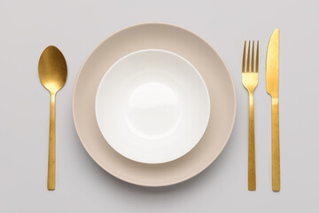 Dishware with golden cutlery on white background