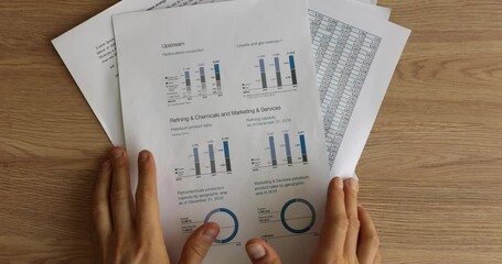Male hands heap up bunch of paper reports and diagrams on wooden office table. Manager makes report about statistics and after work cleans workspace
