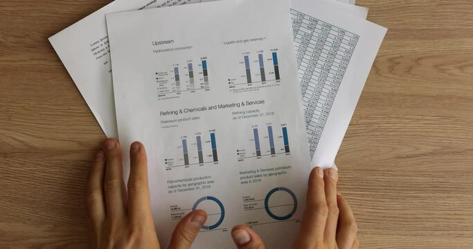 Male hands heap up bunch of paper reports and diagrams on wooden office table. Manager makes report about statistics and after work cleans workspace