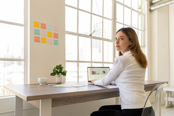 Young woman working at a computer while looking over her shoulder