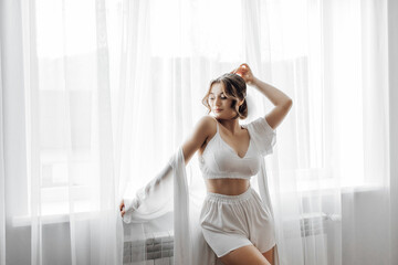 A woman in a wedding dress is standing in front of a mirror. The room is dimly lit, and the...
