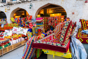 A colorful outdoor storefront display selling vibrantly colored fabrics on blankets, rugs and...