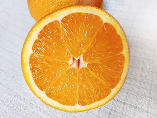 A half of juicy orange on a  white linen tablecloth. Close-up. Macro.