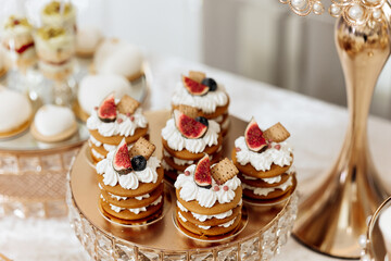 A table with a variety of desserts, including a tray of fruit-topped cakes