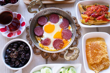 Traditional Turkish Breakfast on the wooden table with copper egg pan and white plates