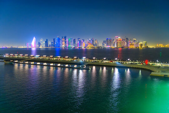 Evening view from the Grand Cruise Terminal of the illuminated and colorful downtown skyline at night along the waterfront corniche in Doha, Qatar.