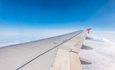 Fototapeta premium View from the airplane window at a beautiful cloudy sky and the airplane wing