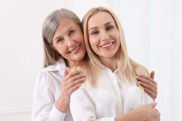 Family portrait of young woman and her mother on white background