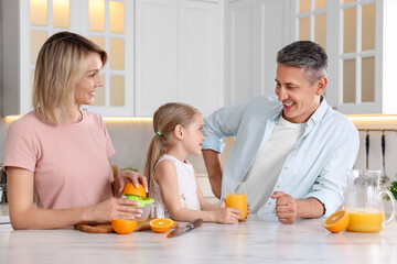 Happy family with juicer and fresh products making juice at white marble table in kitchen