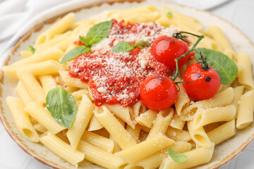 Tasty pasta with tomato sauce, cheese and basil on table, closeup