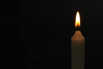 One burning church candle on black background, space for text