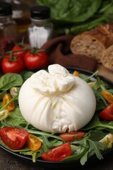 Fresh delicious burrata salad on table, closeup
