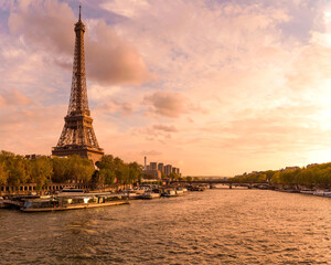 Naklejka premium Sunset Seine - A panoramic sunset view of River Seine, with the iconic Eiffel Tower standing tall at shore and against colorful sky, on a lovely Spring evening. Paris, France.