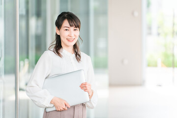 ビルの前でノートパソコンを持つビジネスウーマン・ワーキングママ（ワーキングママ）
