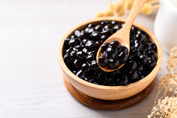 Black tapioca pearls or boba in wooden bowl with spoon, Ingredient in bubble tea