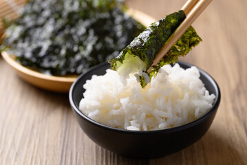 Dried seaweed sheet eating with rice by chopsticks, Asian food © nungning20
