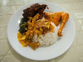 A plate of Padang Rice, served with chicken curry, fried lungs, and vegetables, a very famous specialty from West Sumatra Province, Indonesia.