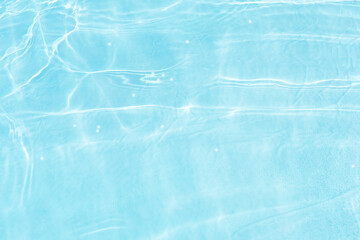 Blue water with ripples on the surface. Defocus blurred transparent blue colored clear calm water surface texture with splashes and bubbles. Water waves with shining pattern texture background.