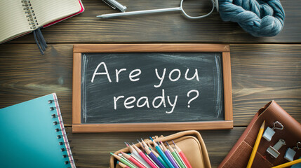 Chalkboard with question "Are you ready?" and notebooks on table. Preparing for exam