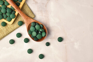 wooden spoon with spirulina and  wooden tray detox tablets pill top view flat lay