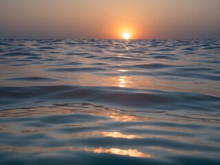 Obraz premium A clear blue ocean that stretches infinitely with a sky the color of a beautiful afternoon with the setting sun reflecting off the water.