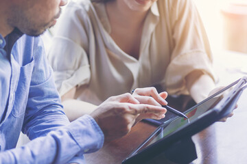Young attractive businesswoman working with touchpad has been guided and consulting by senior colleague.
