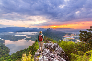 Traveler / climber  stay on top of a mountain and looks into the distance.  Sunrise at Bukit Tabur  / Tabur Hill & Mountain scenery.