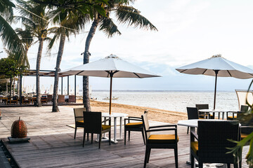 Fototapeta premium Cafe and restaurant chairs with table and umbrella at beach. Famous travel destination in Sanur, Bali, Indonesia.
