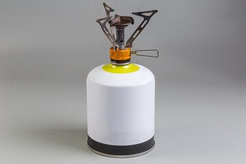 Portable camp gas burner on gas cartridge on gray background