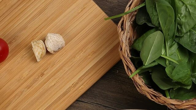Asian style spaghetti with minced chicken spinach thai basil tomato garlic nutmeg olive oil presto sauce served on badge ceramic plate over on rustic wood background wooden board bowl pan zoom