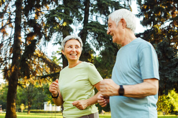 Smiling senior couple jogging in the park. Lifestyle, old people and sport concept.