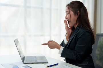 Surprised and happy businesswoman shows joyful expression after viewing news results, business approval results and financial approval results on laptop at office. Startup business growth concept.