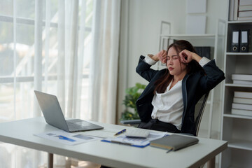 A businesswoman who is tired, stressed, and sore from working for a long time. After waiting for news Unsuccessful business approval results on laptop in office. Startup time concept, office syndrome