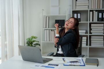 A businesswoman who is tired, stressed, and sore from working for a long time. After waiting for news Unsuccessful business approval results on laptop in office. Startup time concept, office syndrome