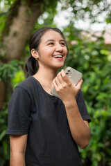 Asian woman playing with smartphone in park