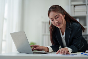 Cheerful and confident Asian businesswoman stands presenting bar chart data from a laptop folder in an online meeting in the office. Startup business ideas, accounting, online marketing.