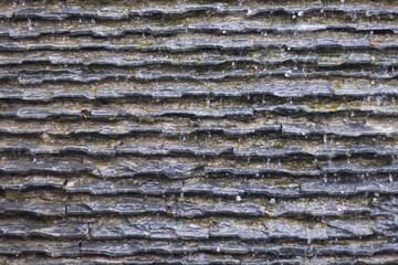 Textured stone wall with water trickling down its surface