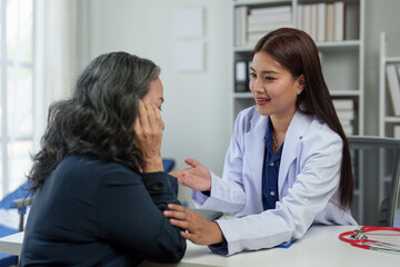 Fototapeta premium An Asian female doctor explains and encourages the struggle of life to a retired female patient who comes for treatment and therapy at a private clinic. Health concept, health insurance.