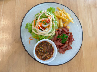Fried pork with sauce, vegetable salad and french fries on a white plate.