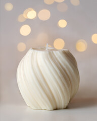 Handmade white candle on pastel background with copy space.