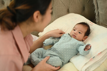 Cute newborn baby lying on soft sofa with mother. Motherhood and child care concept